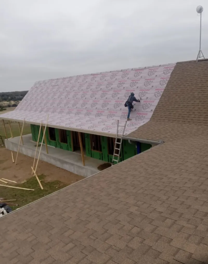 Worker preparing underlayment for a metal roof installation in Vine Grove